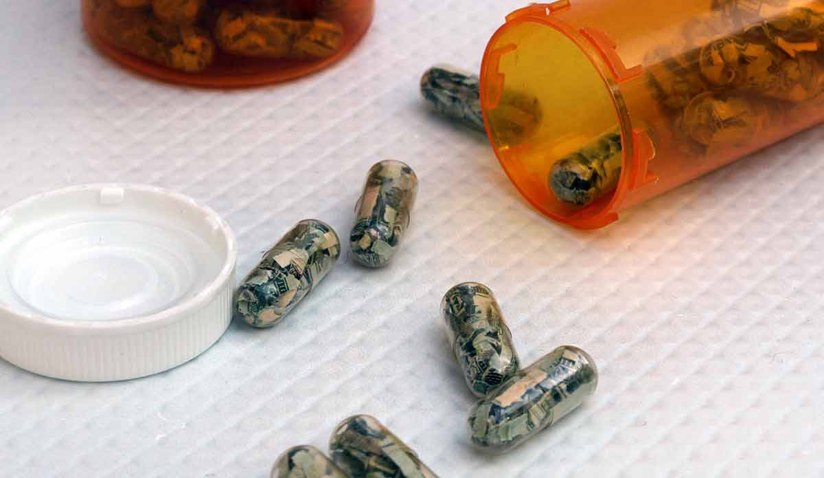 A pill bottle on its side with pill capsules containing shredded paper money