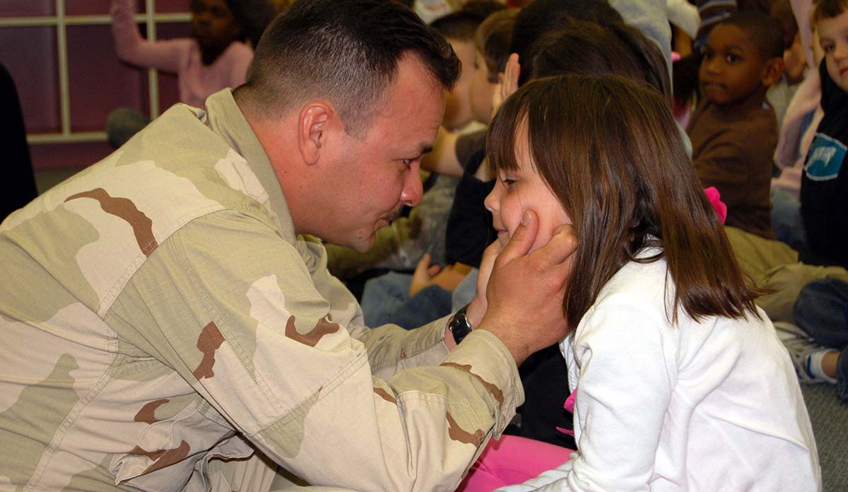 Soldier holding his young daughter's face in his hands