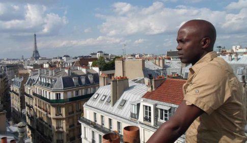 Djamil Bangoura on a rooftop in Paris with Eiffel Tower in the distance