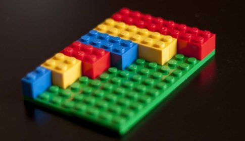 Red, yellow and blue Lego blocks on a green Lego block platform