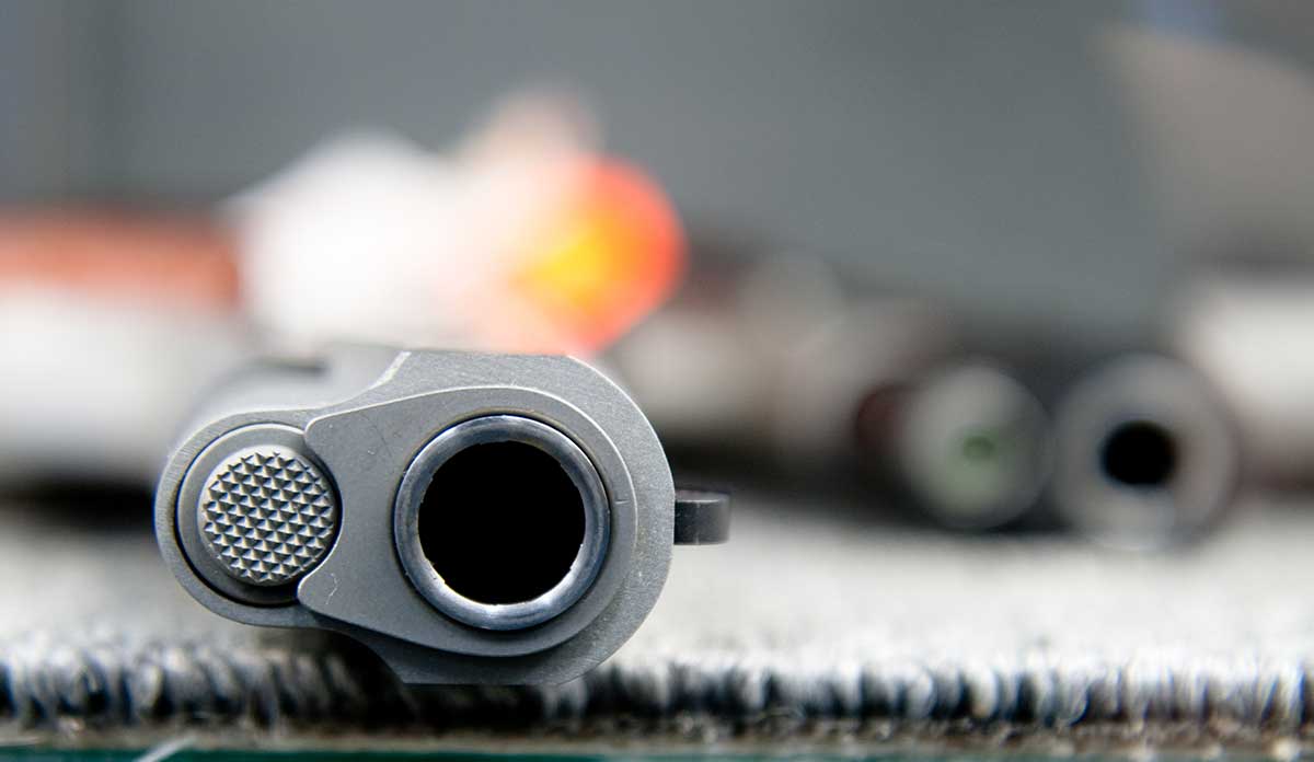 View down the barrel of a pistol lying on carpet