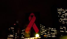 a red AID-awareness ribbon projected on the United Nations buildings at night