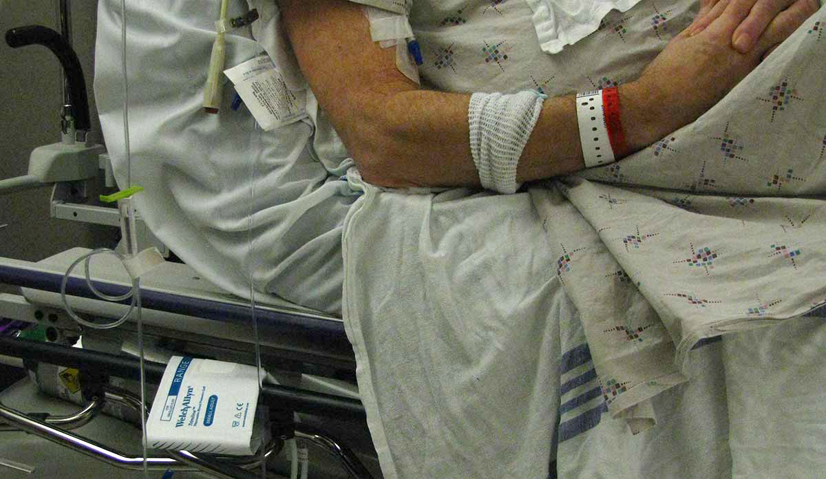 Close-up of a man's arm as he lies in a hospital bed