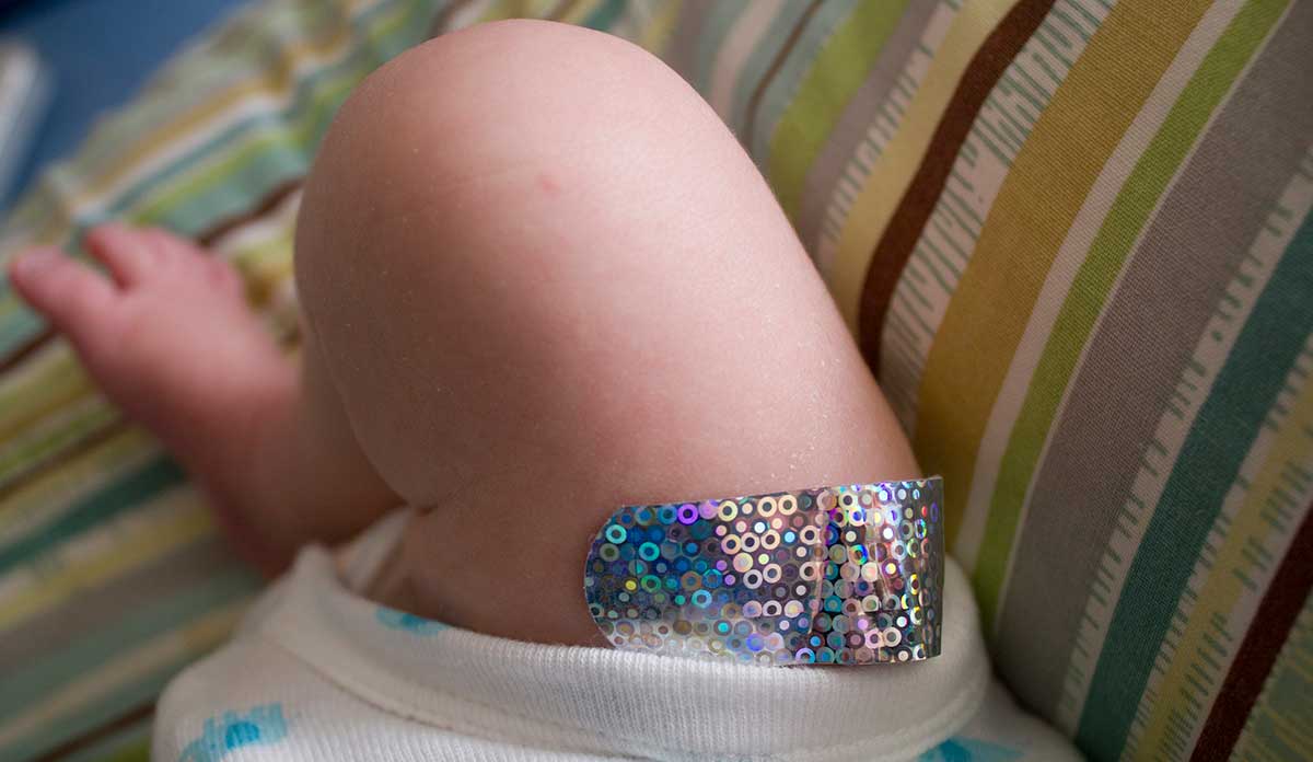 Infants leg with a sparkly vaccination bandaid