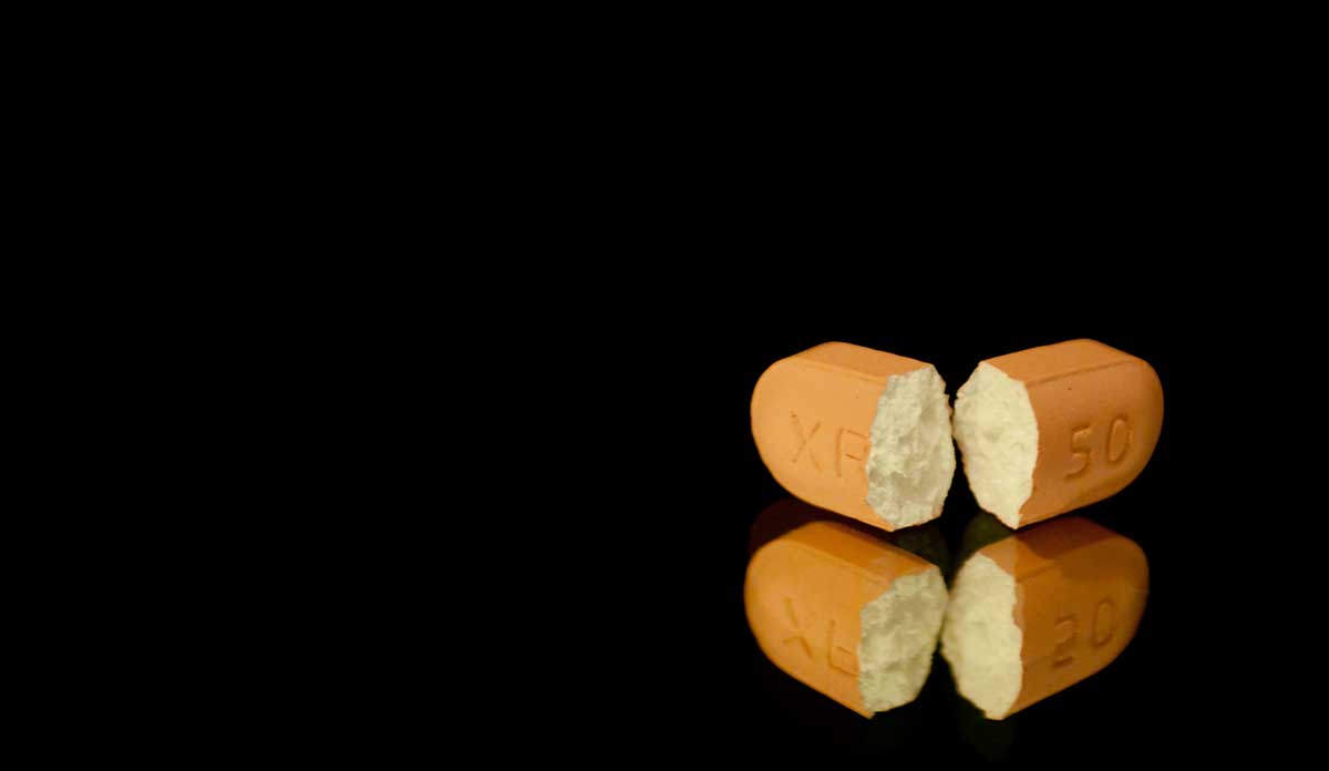A pill broken in half on a black background