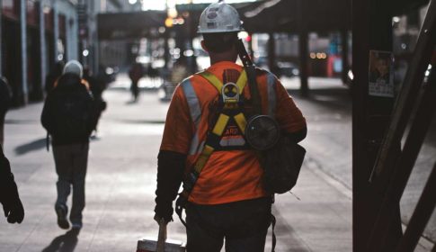 Construction worker in helmet carrying lunch cooler