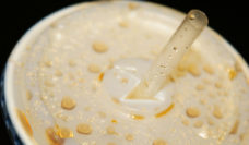 Closeup of the top of a cup of soda with a plastic top and straw