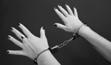 black and white photo of a women's hands in handcuffs