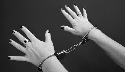 black and white photo of a women's hands in handcuffs