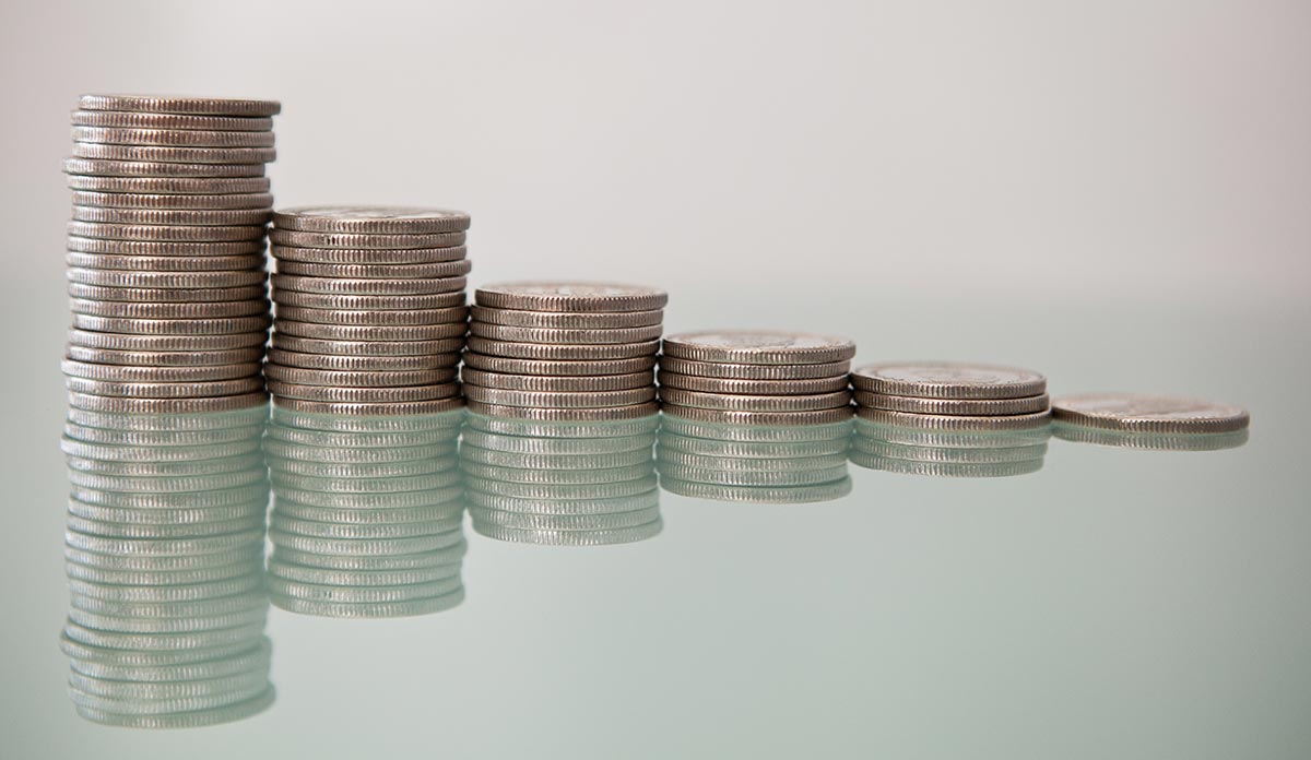 Six stacks of quarters going from tall to short, sitting on a reflective glass surface