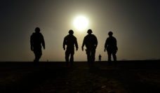 Soldiers silhouetted against a hazy sun and sky