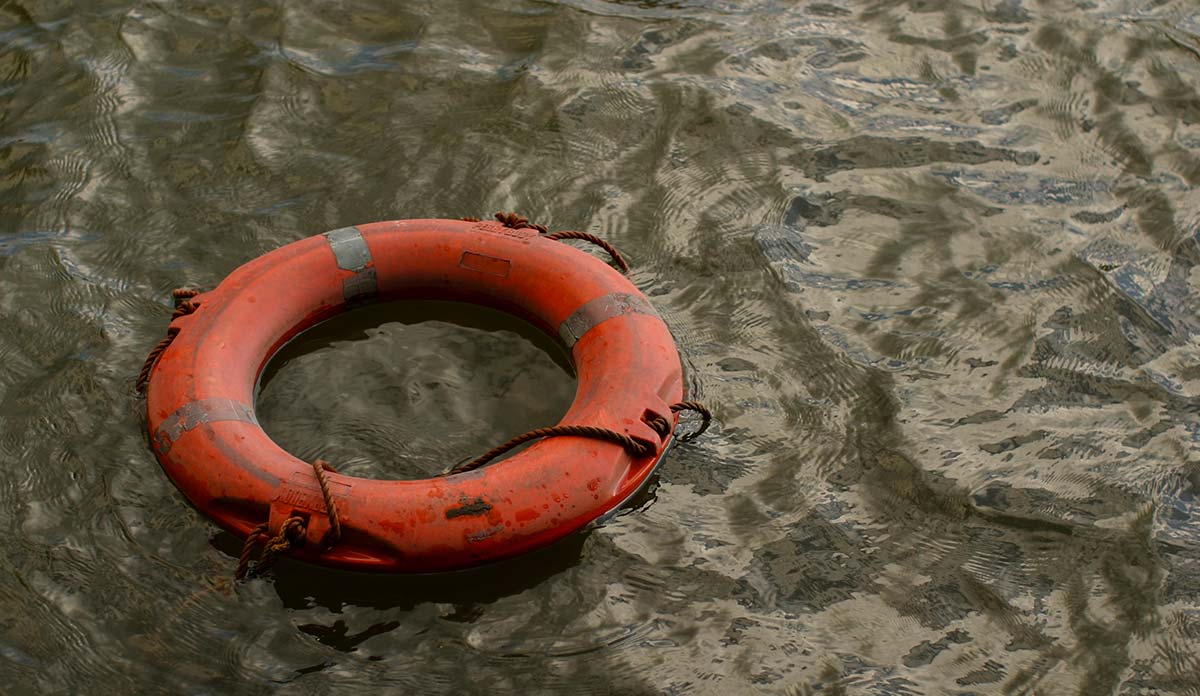 Life preserver ring floating in a dirty river