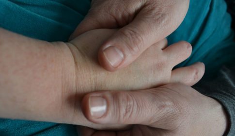 Doula's hands holding a patient's hands