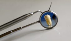 Dental pick and mirror with a tooth reflected in it