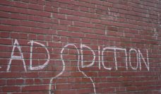 A brick wall with the word addiction written in chalk