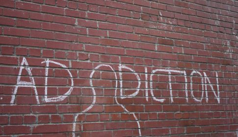 A brick wall with the word addiction written in chalk