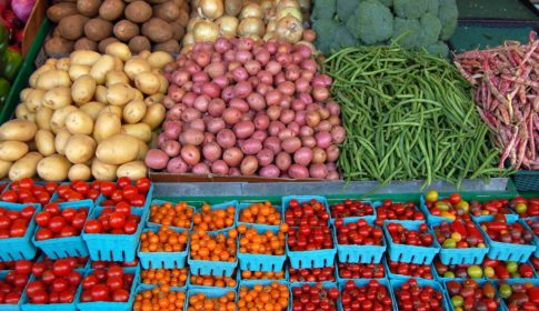 A produce market with tomatoes, potatoes, and other vegetables