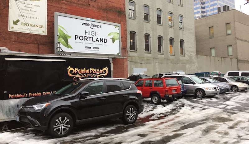 Marijuana advertising on a billboard above a parking lot