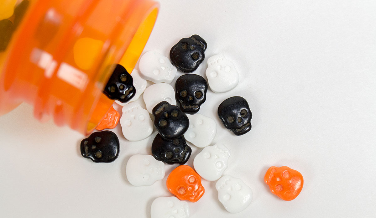 Black, white, and orange skull candies coming out of a prescription bottle