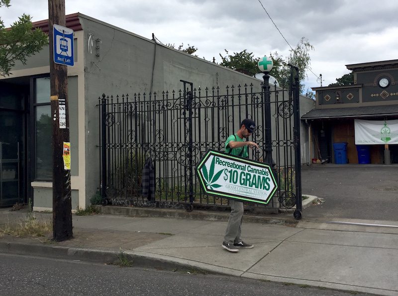 Man waving a sign advertising marijuana
