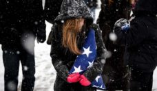 Girl holding a folded flag in the snow