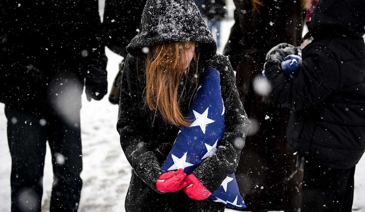 Girl holding a folded flag in the snow