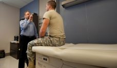 Doctor has soldier follow his finger with his eyes during a neurologic exam