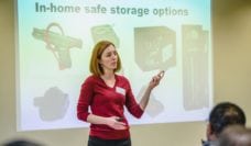 Emmy Betz standing in front of a projection of gun safe storage options