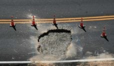 Sinkhole on a street with orange cones around it