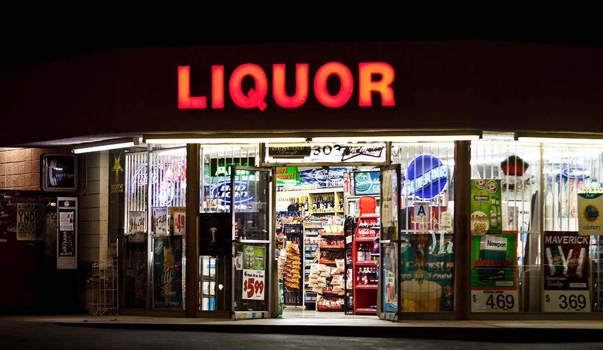 Store at night with large neon letters spelling LIQUOR