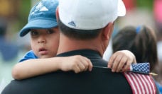 Boy in his father's arms holding a small American flag