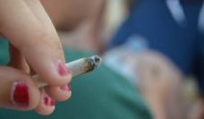 Hand holding a joint with a figure reclining in the background