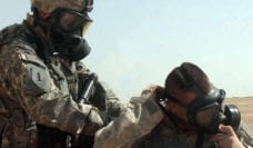 Two soldiers putting on gas masks