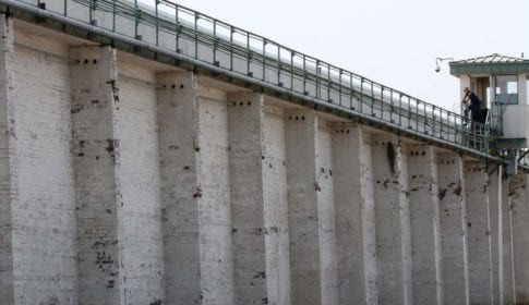 A prison guard in a guard tower on top of a high prison wall