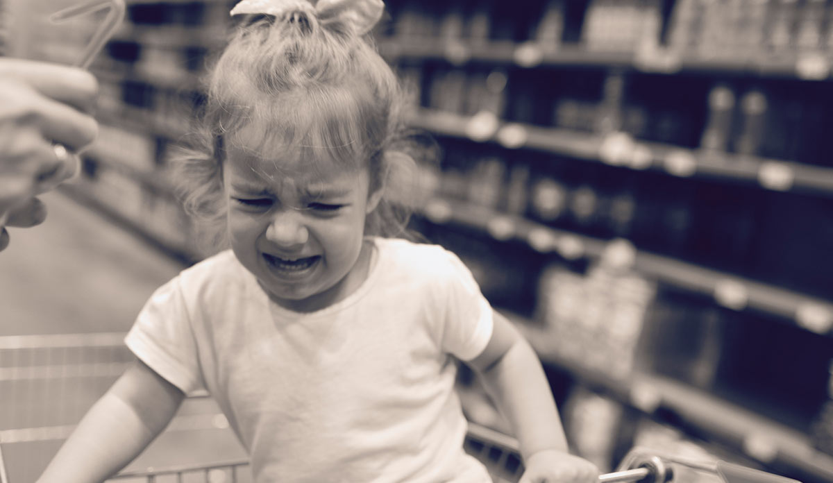 Toddler crying in a grocery cart