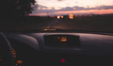 Looking out the windshield of a car at the highway at dusk