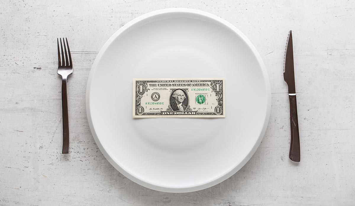 A fork, knife and plate with a dollar bill on it
