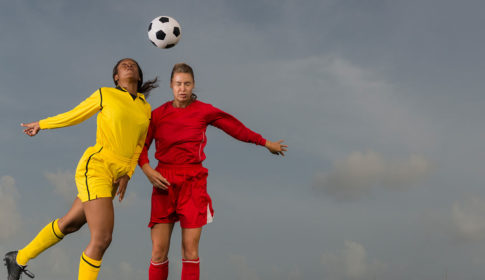 Two women soccer players heading the ball
