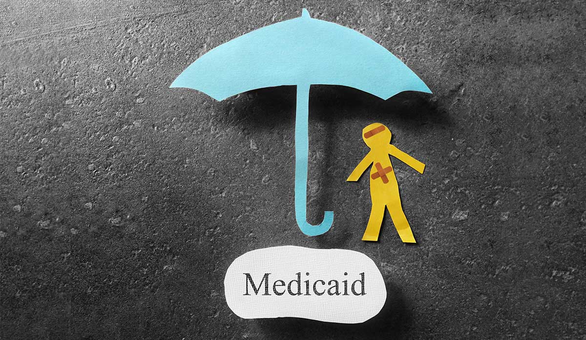 Paper cutouts of an umbrella and a person over the word Medicaid