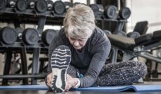 Older woman stretching her leg on a mat a the gym