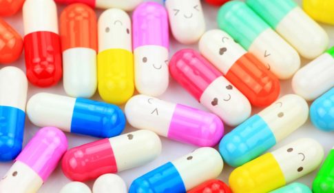 Brightly color pill capsules with smiling faces drawn on them