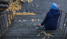 Adolescent in hoodie smoking on steps