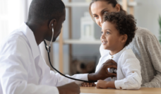 young patient of color being examined by dr.