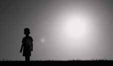 Silhouette of child standing alone in field