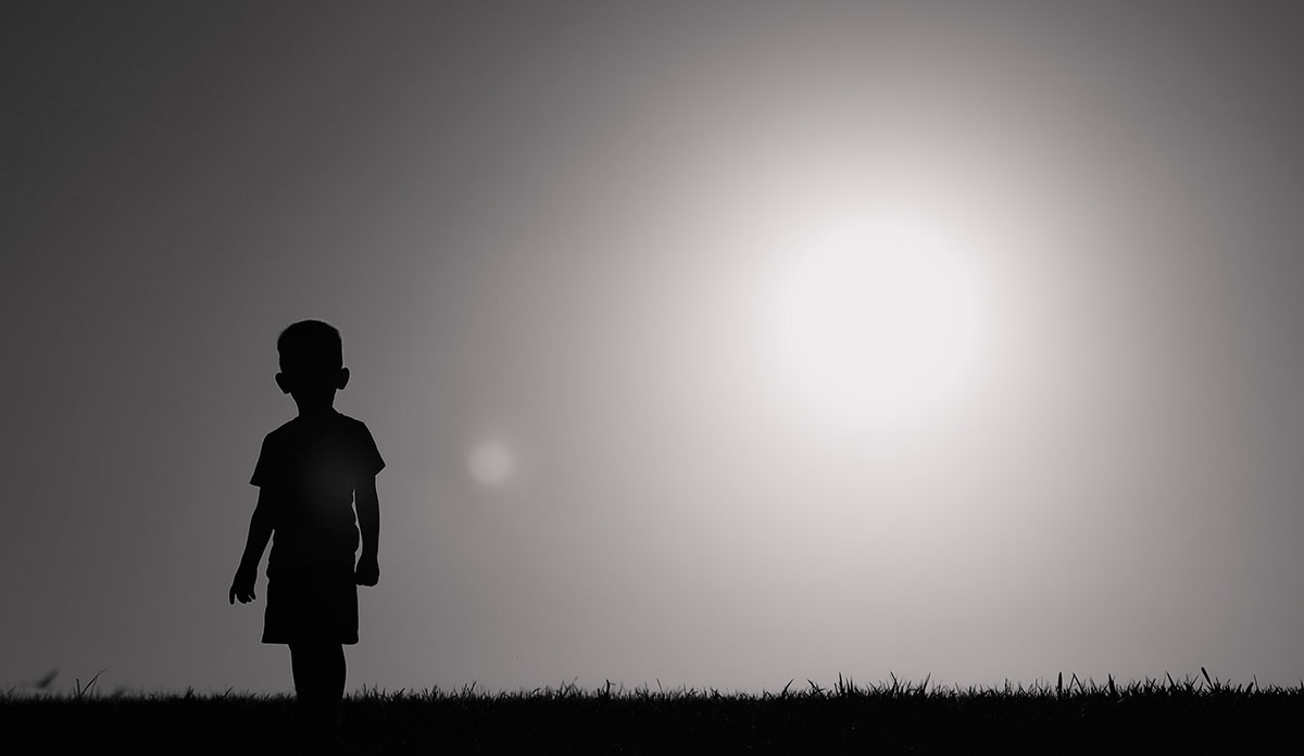Silhouette of child standing alone in field
