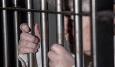 woman with gray hair behind prison bars
