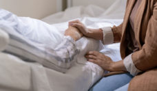 holding hand of person in hospital bed