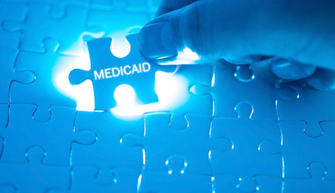 holding puzzle piece with medicaid on it