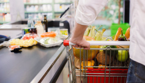 person at grocery store checkout with lots of food