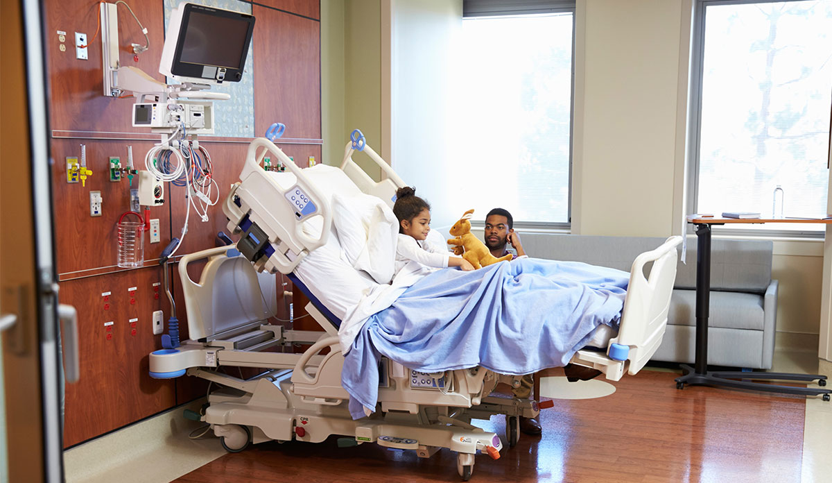 child in hospital bed with parent